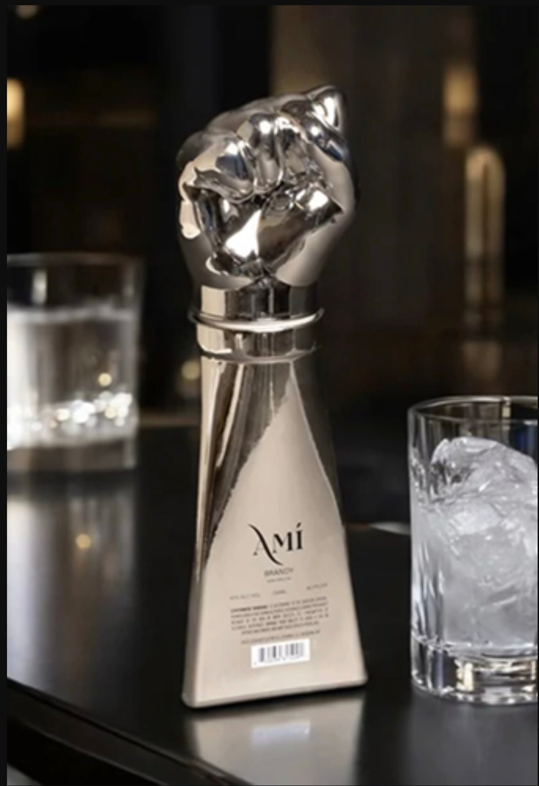 amí brandy silver hand-shaped bottle beside a glass
