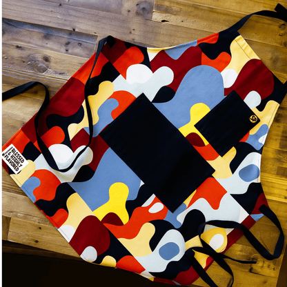 Beryl apron with red, blue, gold, and black abstract print, laid flat
