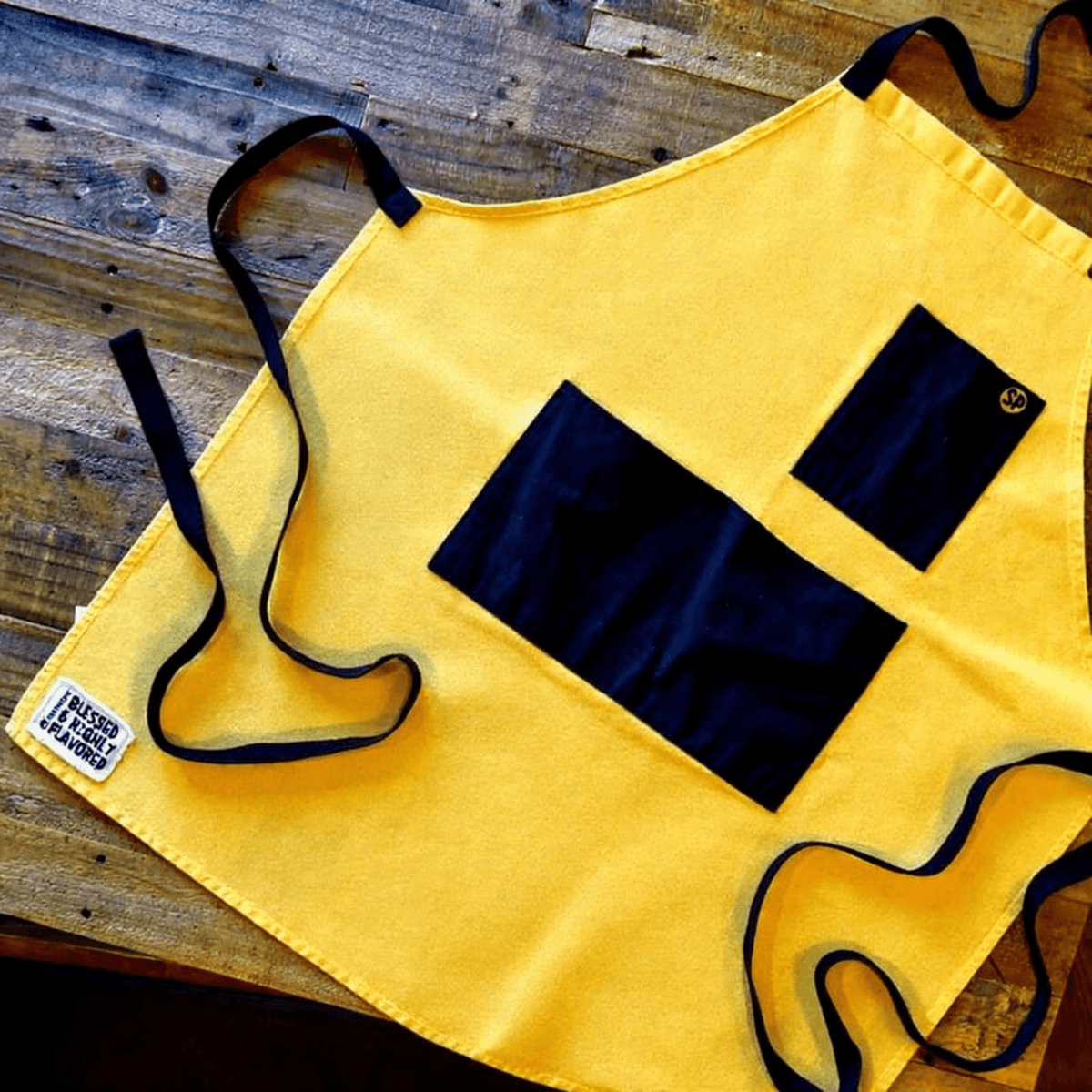 Cornbread Gold apron with black pockets laid flat