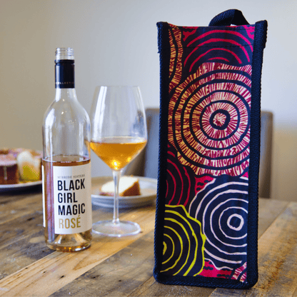 Pink and yellow circular-pattern wine bag styled beside a bottle and glass